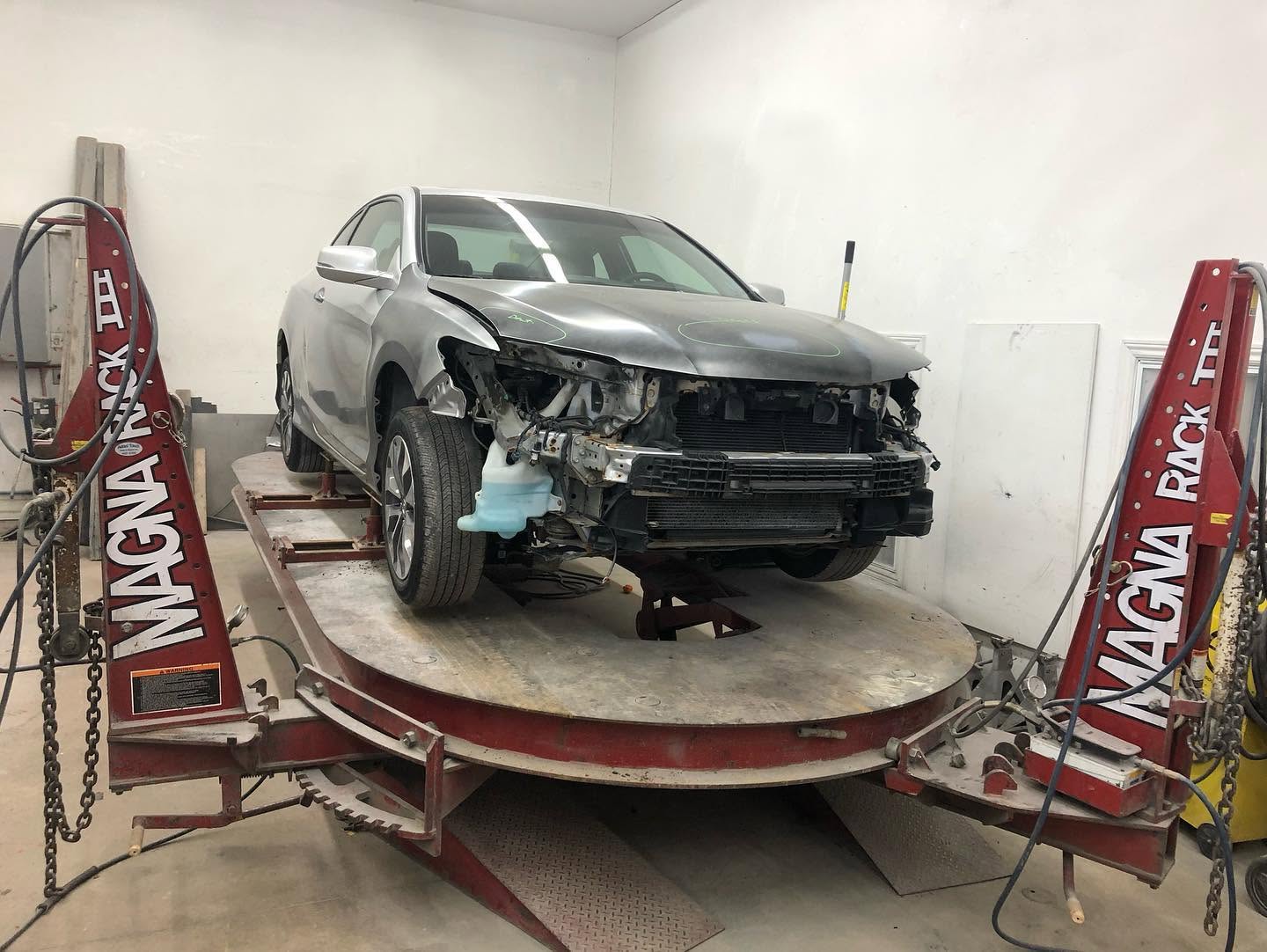 Silver Honda Accord coupe with front-end collision damage on the frame rack