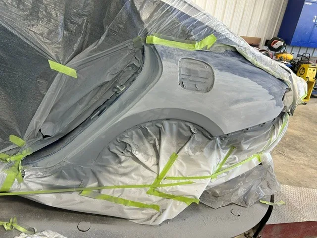The same sedan masked off and prepped for refinishing in the booth